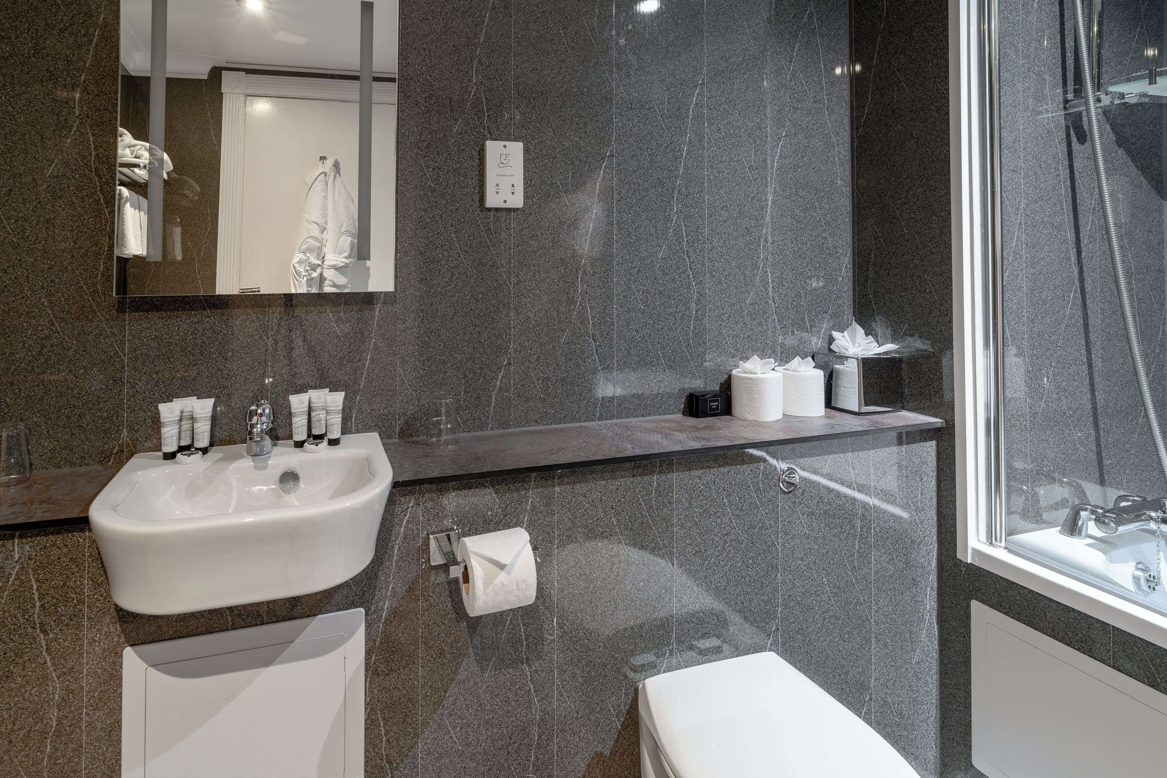 Ein modernes Badezimmer mit Marmorwaschbecken, einem Spiegel, einer Toilette und einer Duschkabine.
