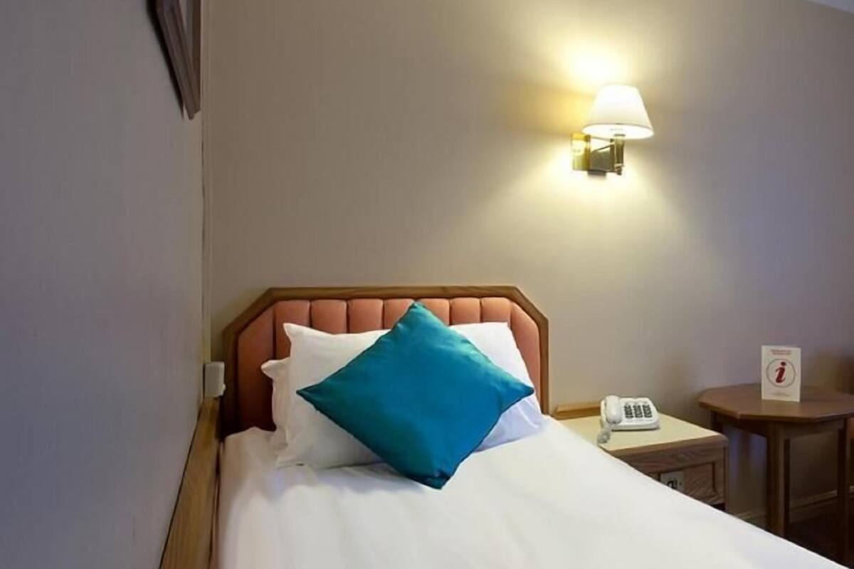 Une chambre d’hôtel avec un lit, une table de chevet, une lampe et un téléphone.