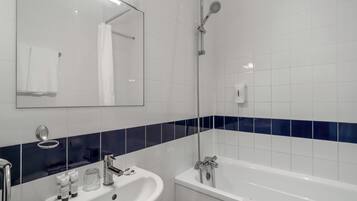 Un bagno con lavandino bianco, uno specchio, una doccia e una vasca da bagno.