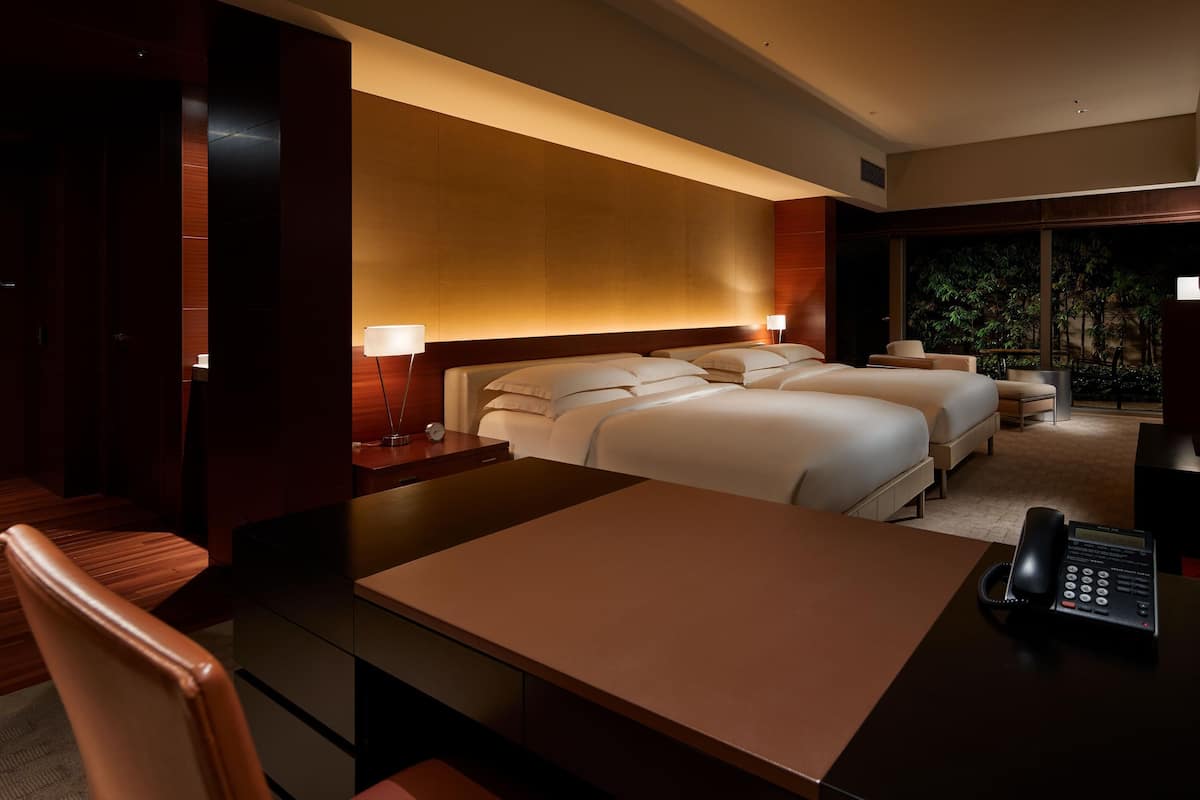 A hotel room with a large bed, a desk, a chair, a TV, and a phone.