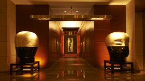 A hallway with two large spherical sculptures on pedestals, a central illuminated wall, and a reflective floor. - Grand Hyatt Tokyo (Tokyo)