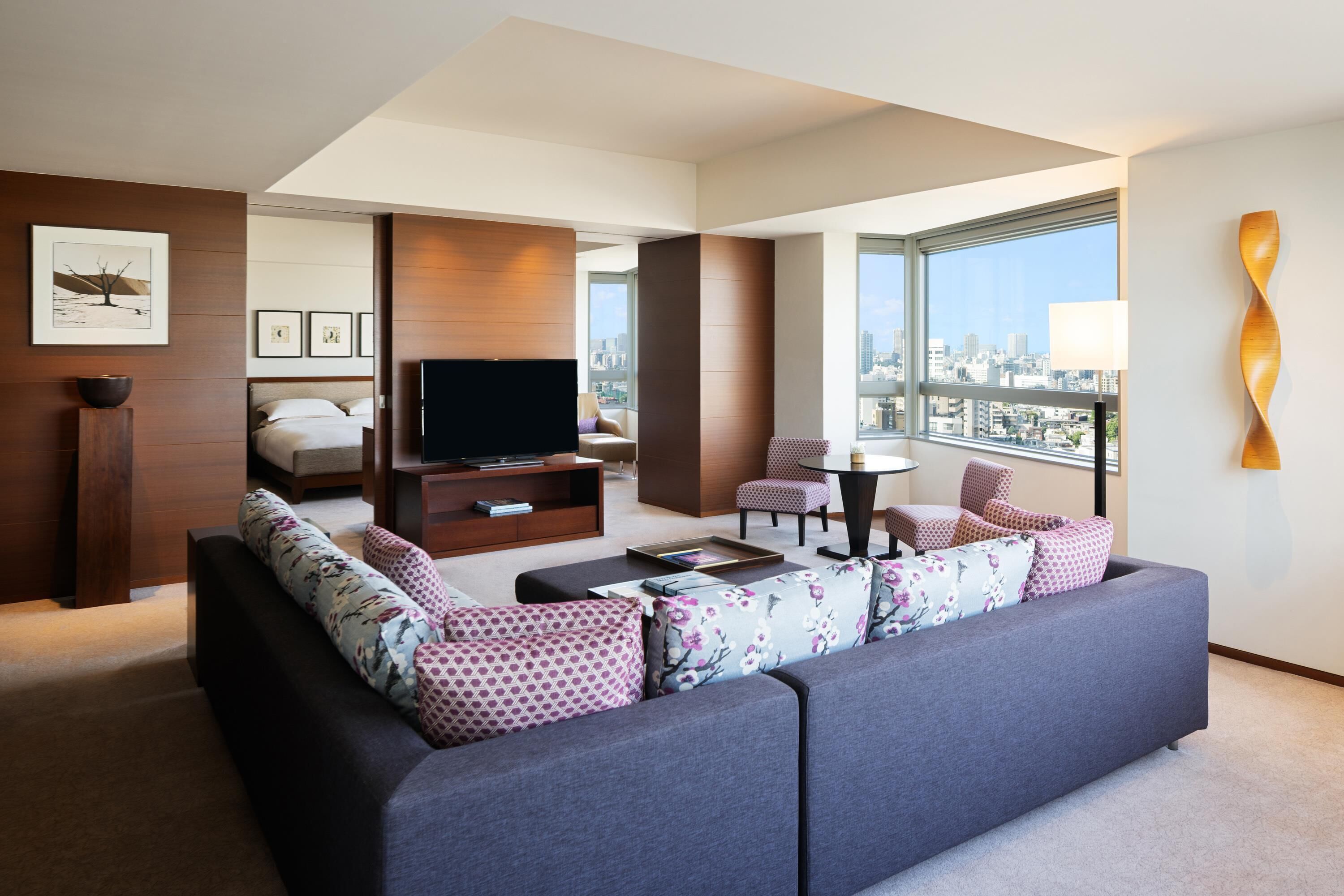 A modern living room with a sofa, TV, and city view.