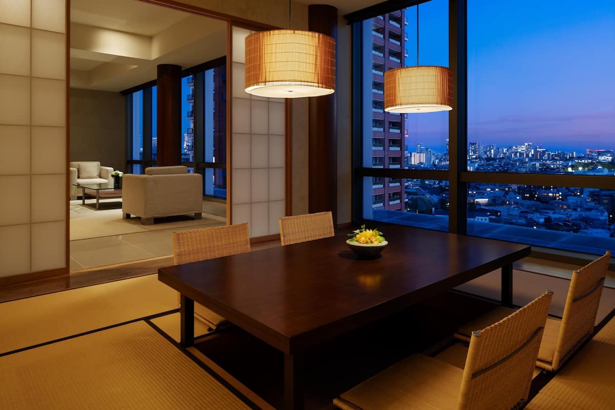 A modern dining area with a wooden table, woven chairs, and a city view.