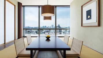 A dining area with a table, chairs, a hanging light fixture, and a framed picture on the wall.