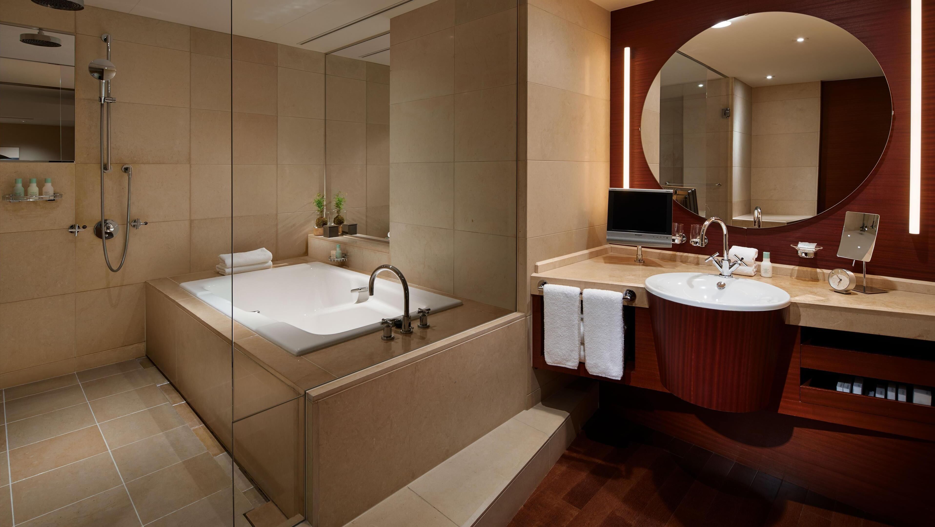 A modern bathroom with a bathtub, a sink, a shower, and a large mirror.
