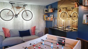 A room with a sofa, a foosball table, and bicycles mounted on the wall. - Mercure Bordeaux Centre Ville (Bordeaux)