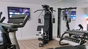 Un gimnasio con equipo cardiovascular, máquinas de pesas y mancuernas.