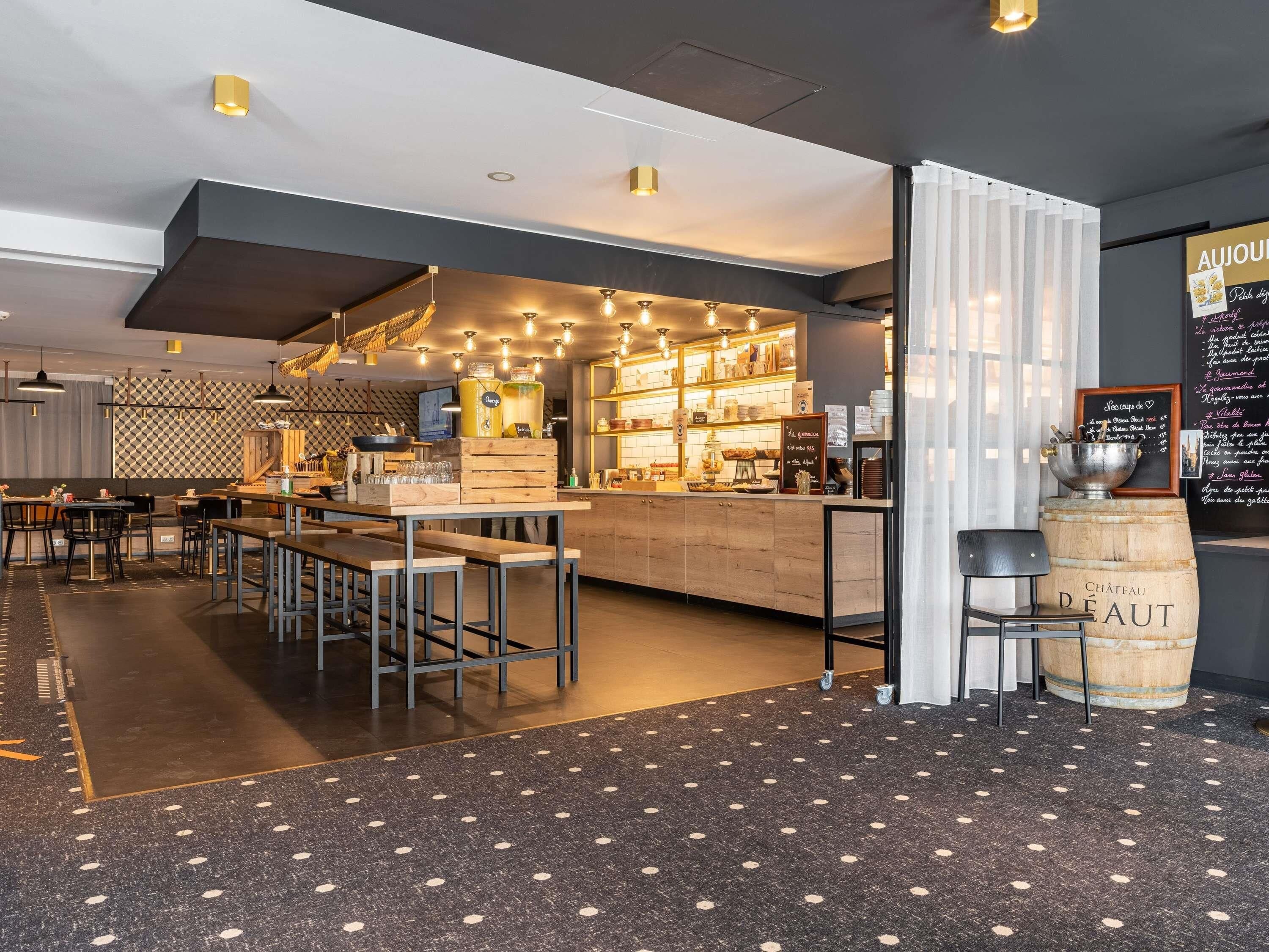 A modern cafe with a wooden counter, seating area, and a chalkboard menu.