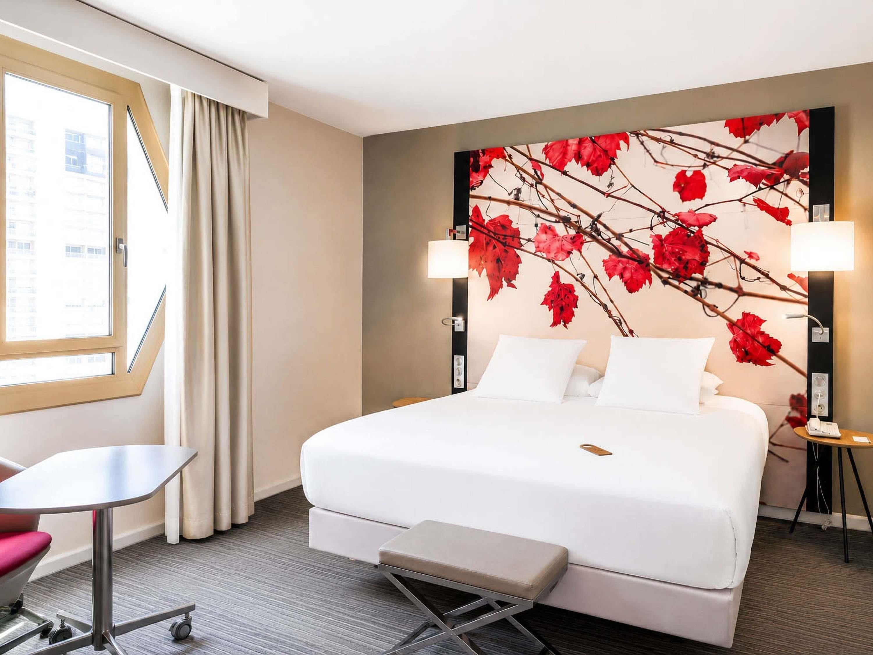 Ein Hotelzimmer mit Bett, Schreibtisch, Stuhl und einem Vorhangfenster.