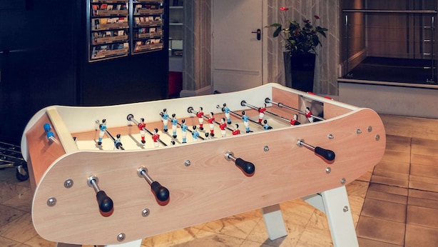 A foosball table in a room with tiled flooring and a potted plant in the background. - Mercure Bordeaux Centre Ville (Bordeaux)