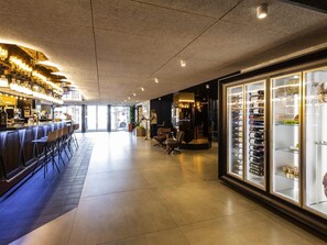 Eine moderne Bar mit einer langen Theke, Barhocker und einem Weinkühlschrank.