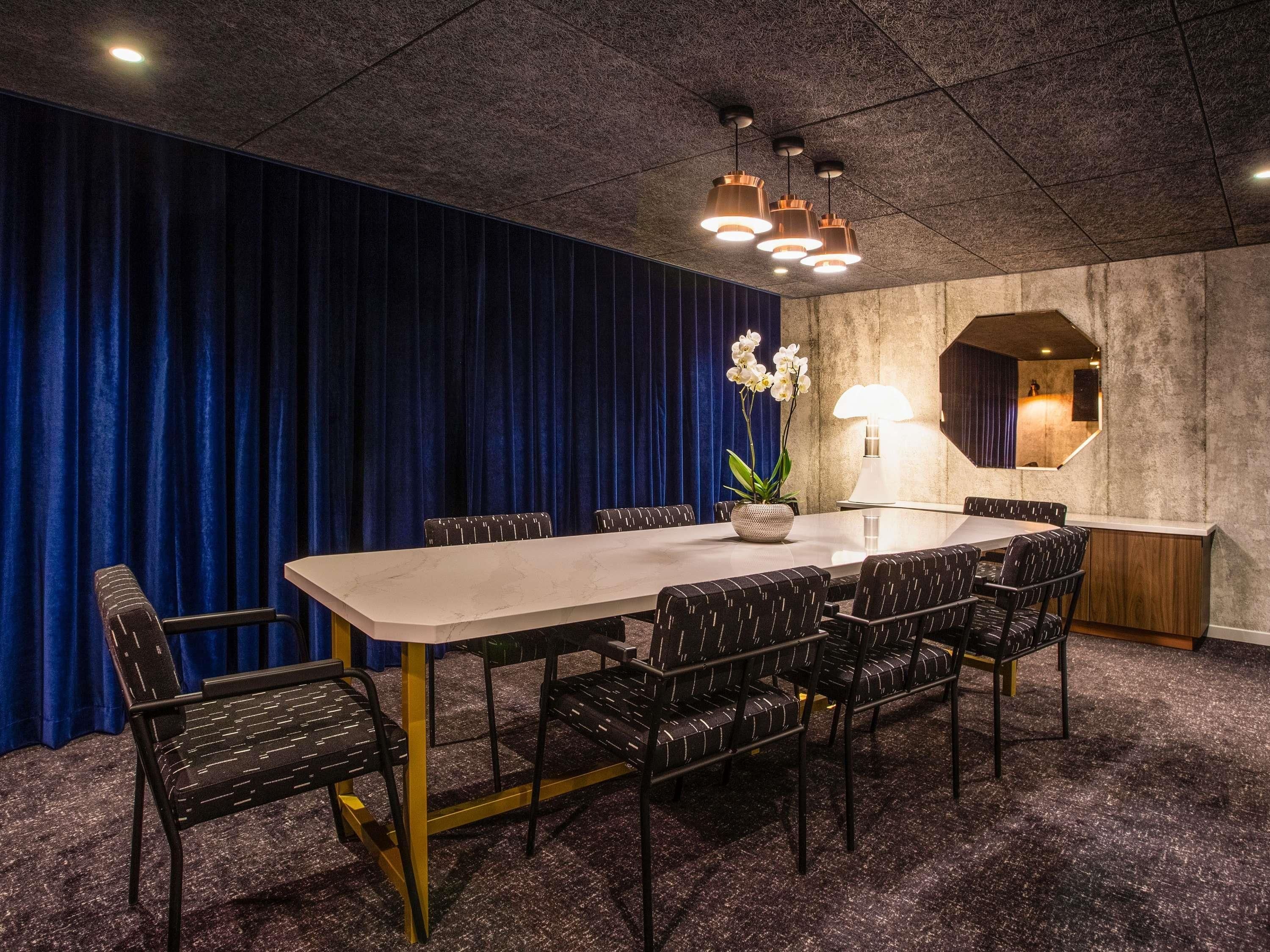 Une salle de conférence avec une longue table, des chaises, une plante en pot et une lampe.