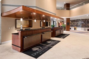 A hotel reception area with a wooden reception desk, a large abstract painting, and a Starbucks sign. - Doubletree by Hilton Somerset Hotel & Conf Ctr (Somerset)