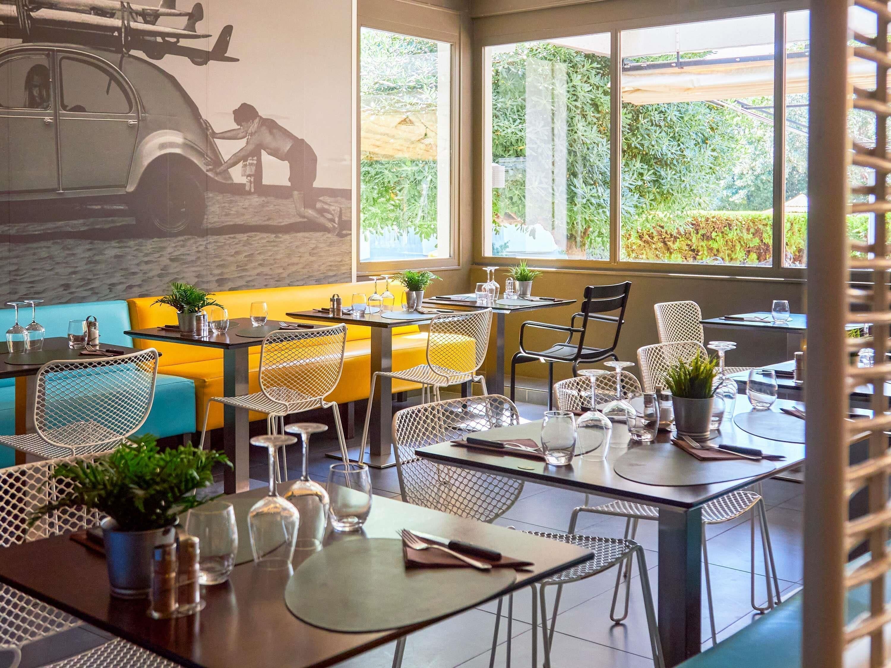 Interior de restaurante com mesas, cadeiras e um mural na parede.