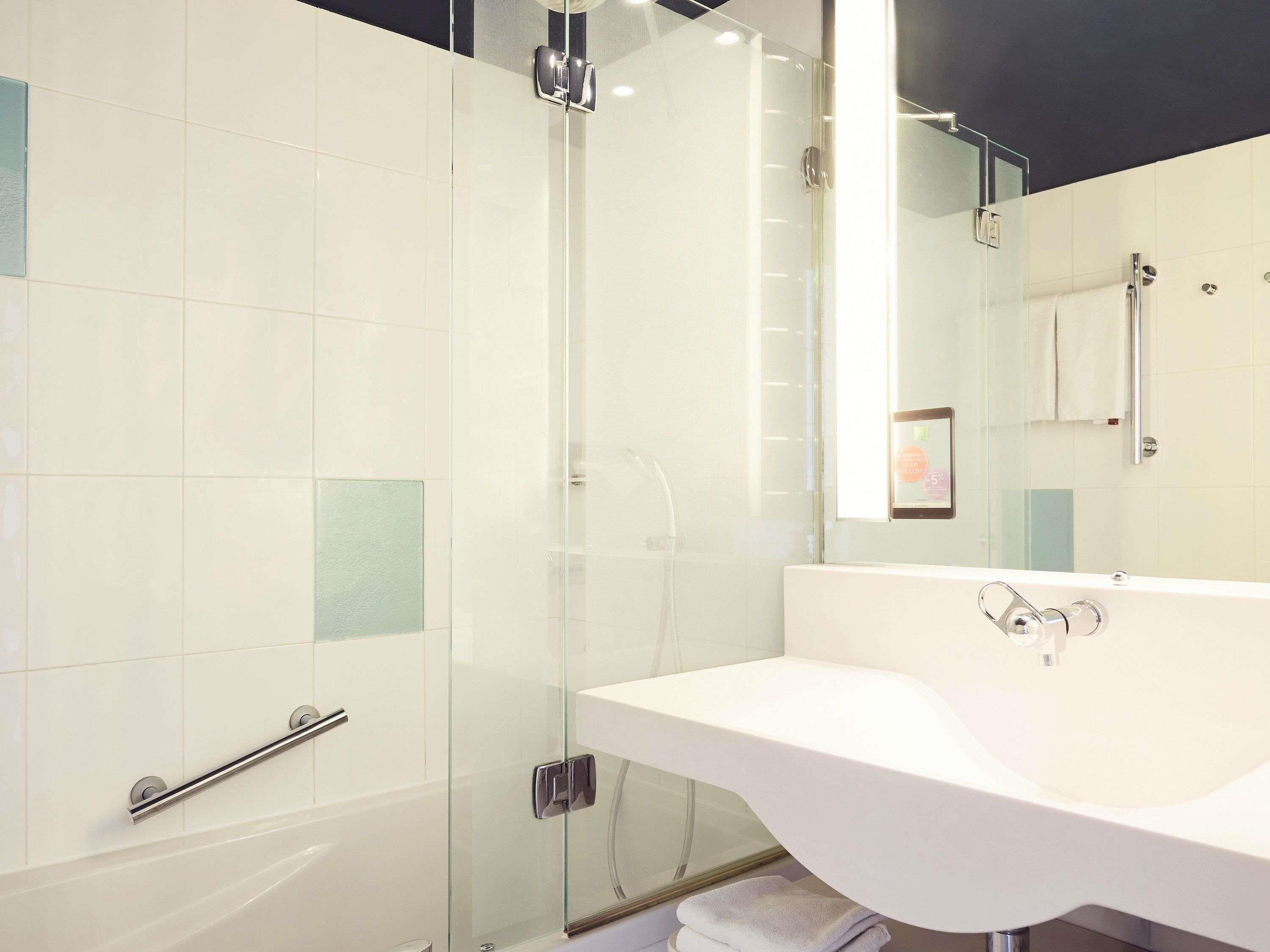 A modern bathroom with a glass-enclosed shower, a white sink, and a mirror.