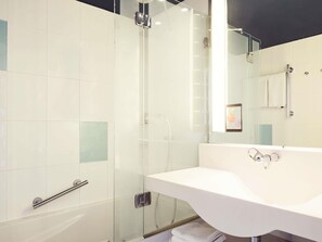 Une salle de bain moderne avec une douche à parois de verre, un lavabo blanc et un miroir.