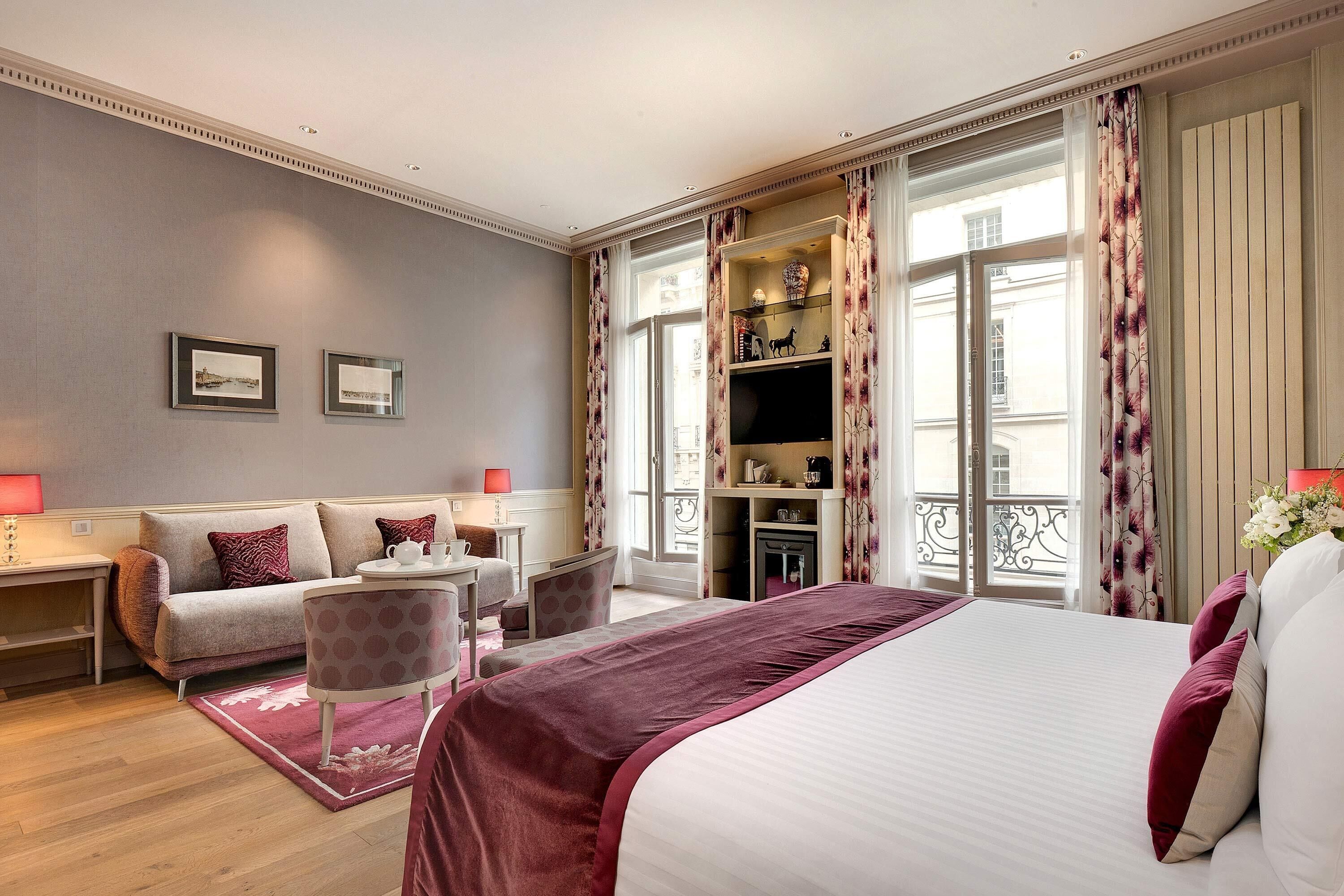 Una habitación de hotel con cama, sofá, escritorio y televisión.