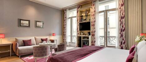Una habitación de hotel con cama, sofá, escritorio y televisión.