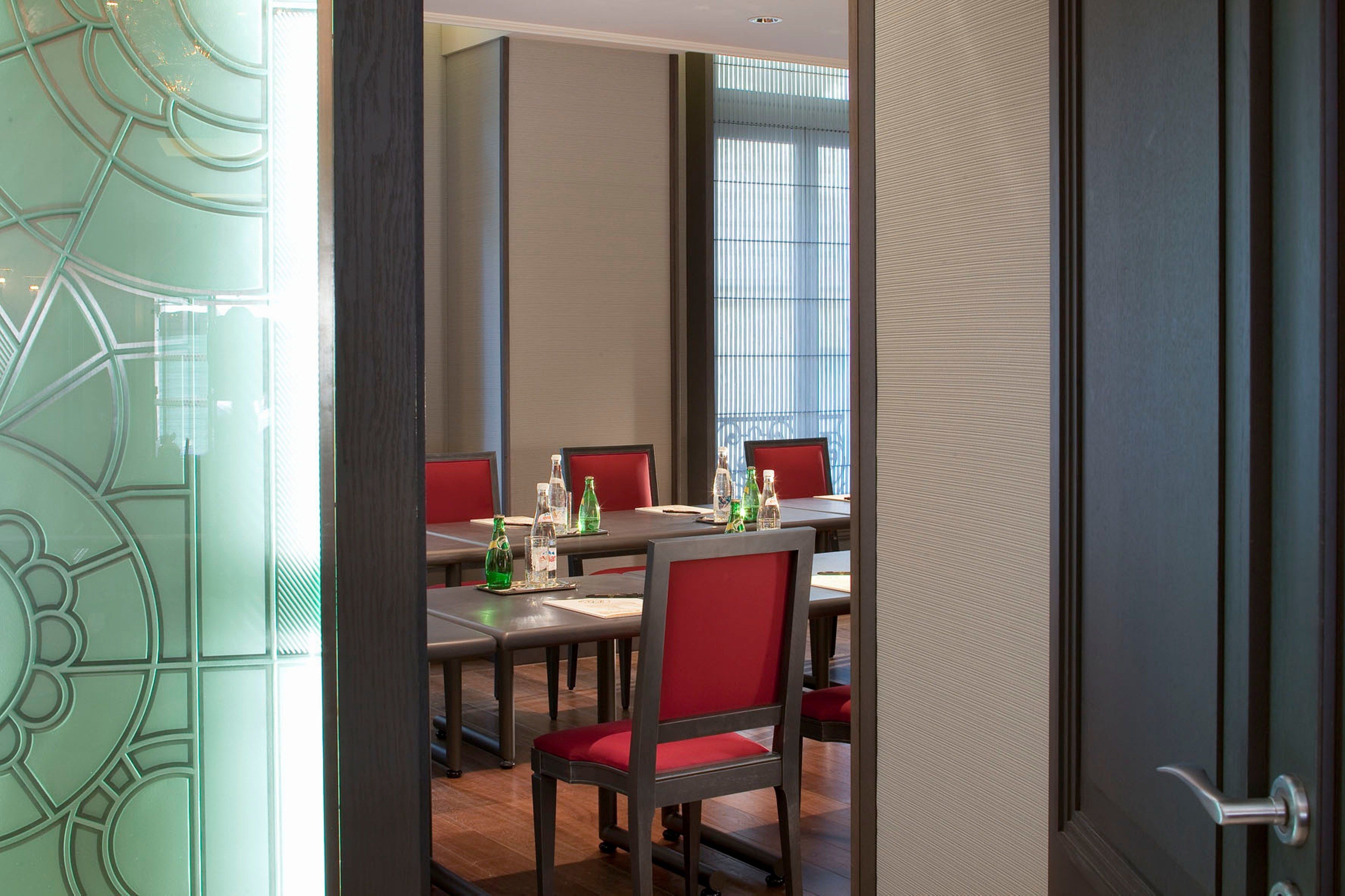 A dining area with tables and chairs, a glass partition, and a door.