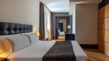 A hotel room with a large bed, a wardrobe, and a desk with a lamp.