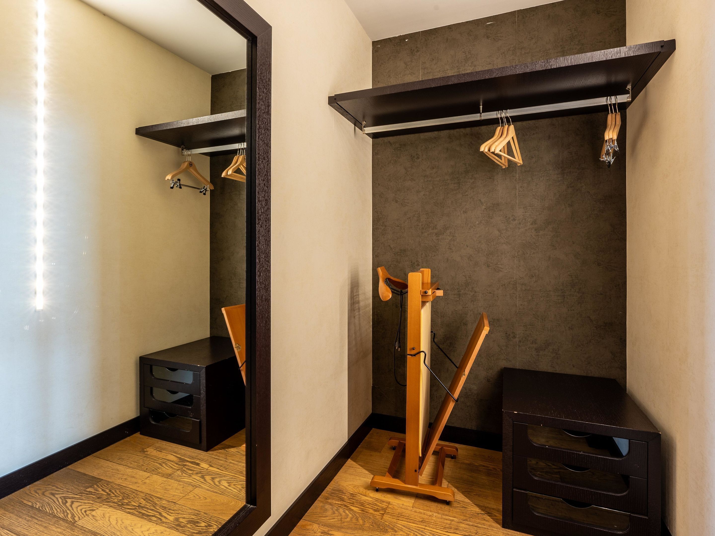 Un baño moderno con piso de madera, un mueble de tocador negro, un espejo y un perchero para toallas.