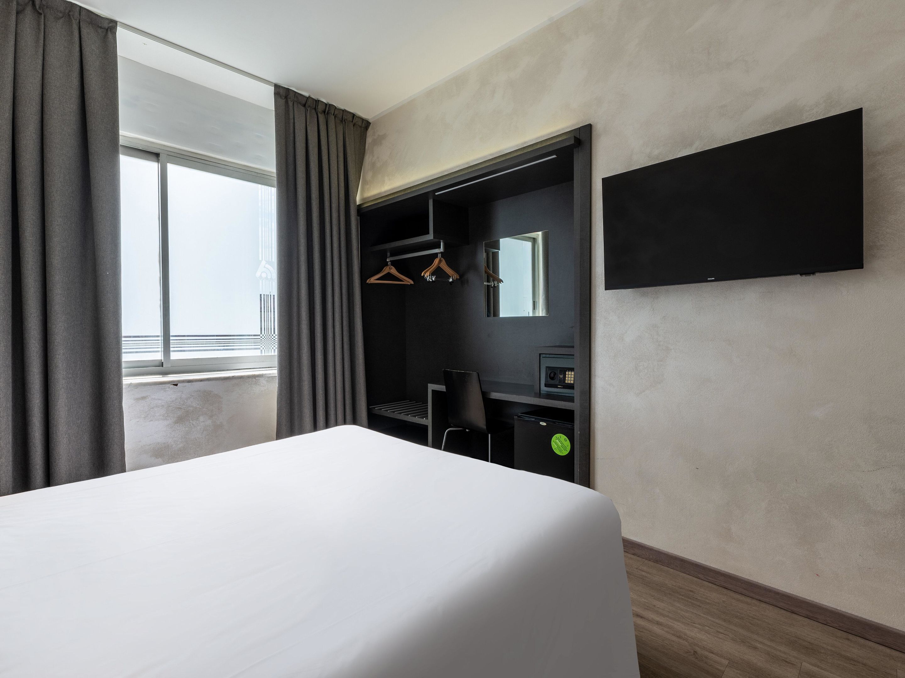 Hotelkamer met een bed, een bureau, een stoel, een spiegel en een televisie.