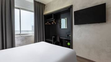Hotelkamer met een bed, een bureau, een stoel, een spiegel en een televisie.