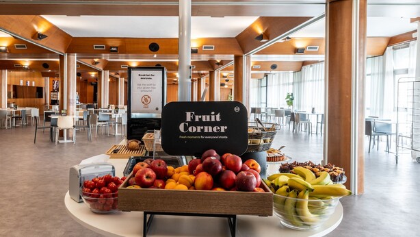 A fruit corner in a modern dining area with a sign indicating gluten-free options. - B&B Hotel Borgaro Torinese (Borgaro Torinese)