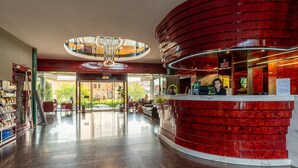A hotel lobby with a curved reception desk, a chandelier, and a glass door leading outside. - B&B Hotel Borgaro Torinese (Borgaro Torinese)