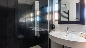 A modern bathroom with a glass-enclosed shower, a white sink, and a large mirror.