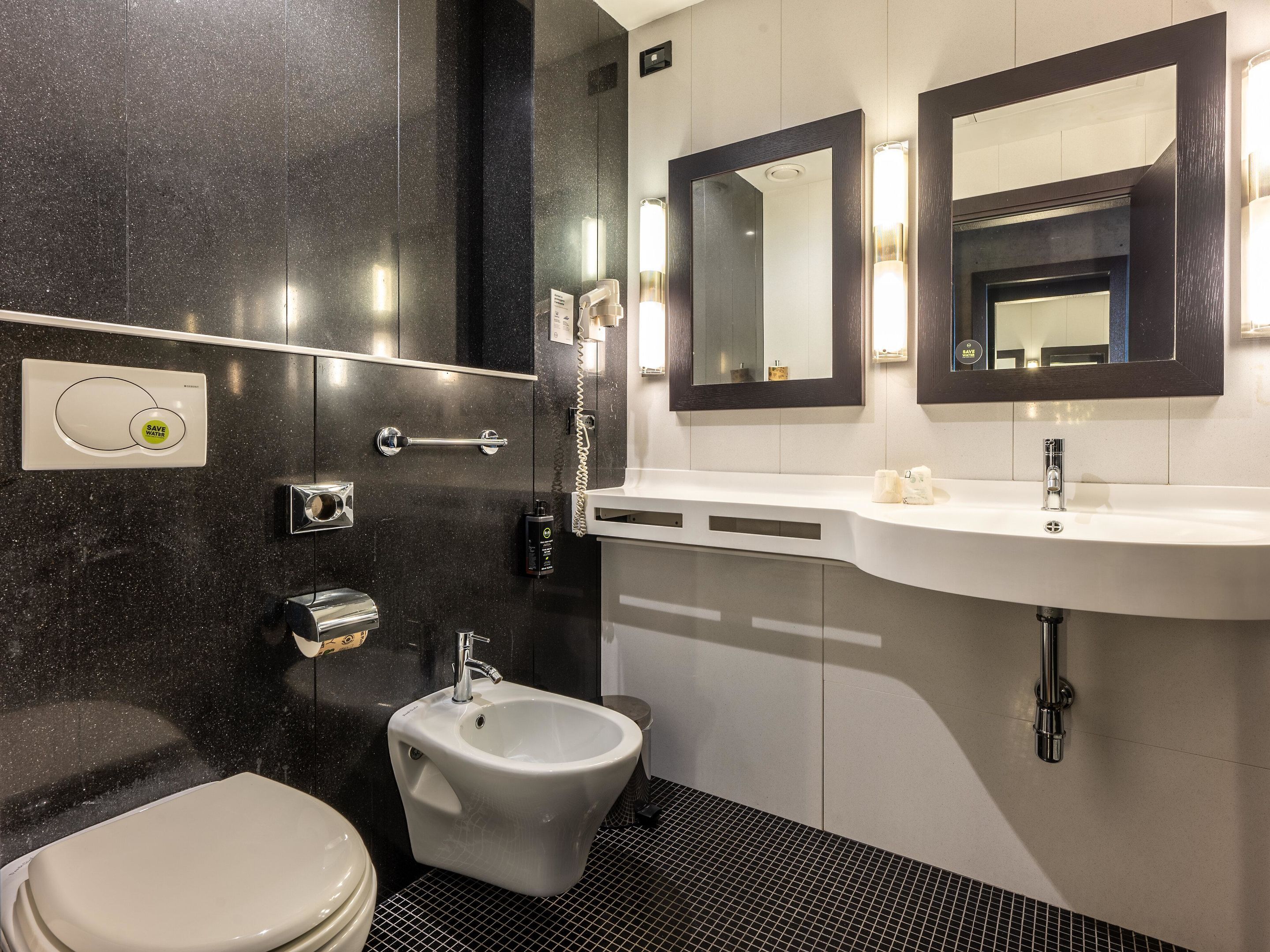 Ein modernes Badezimmer mit einer Bidet, einer Toilette, einem Waschbecken und zwei Spiegeln.