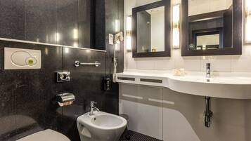 Ein modernes Badezimmer mit einer Bidet, einer Toilette, einem Waschbecken und zwei Spiegeln.