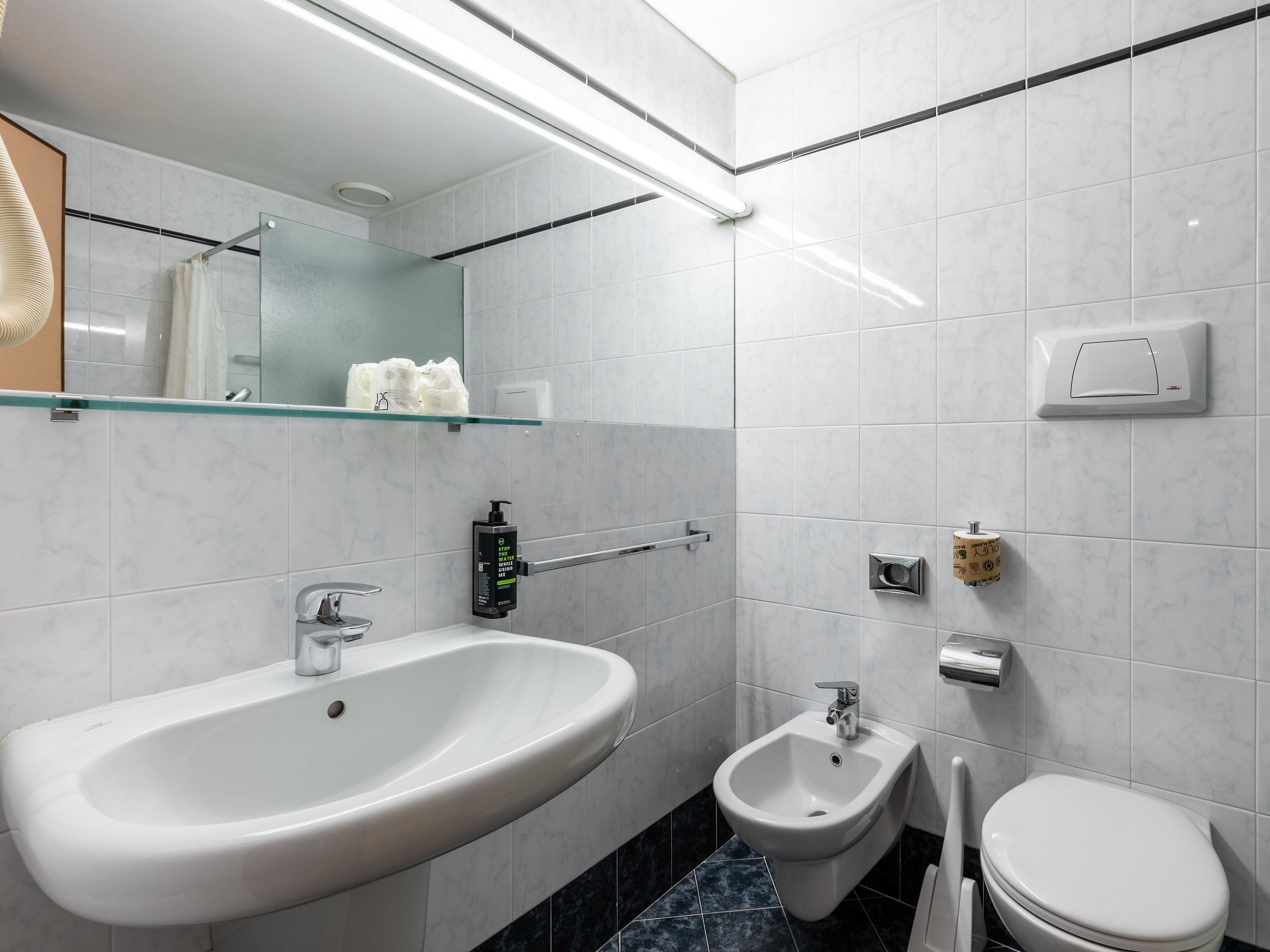 Un baño moderno con lavamanos, bidé y retrete blancos.