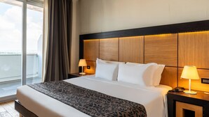 A hotel room with a large bed, two bedside tables with lamps, a view of the sky through a window, and a balcony. - B&B Hotel Borgaro Torinese (Borgaro Torinese)