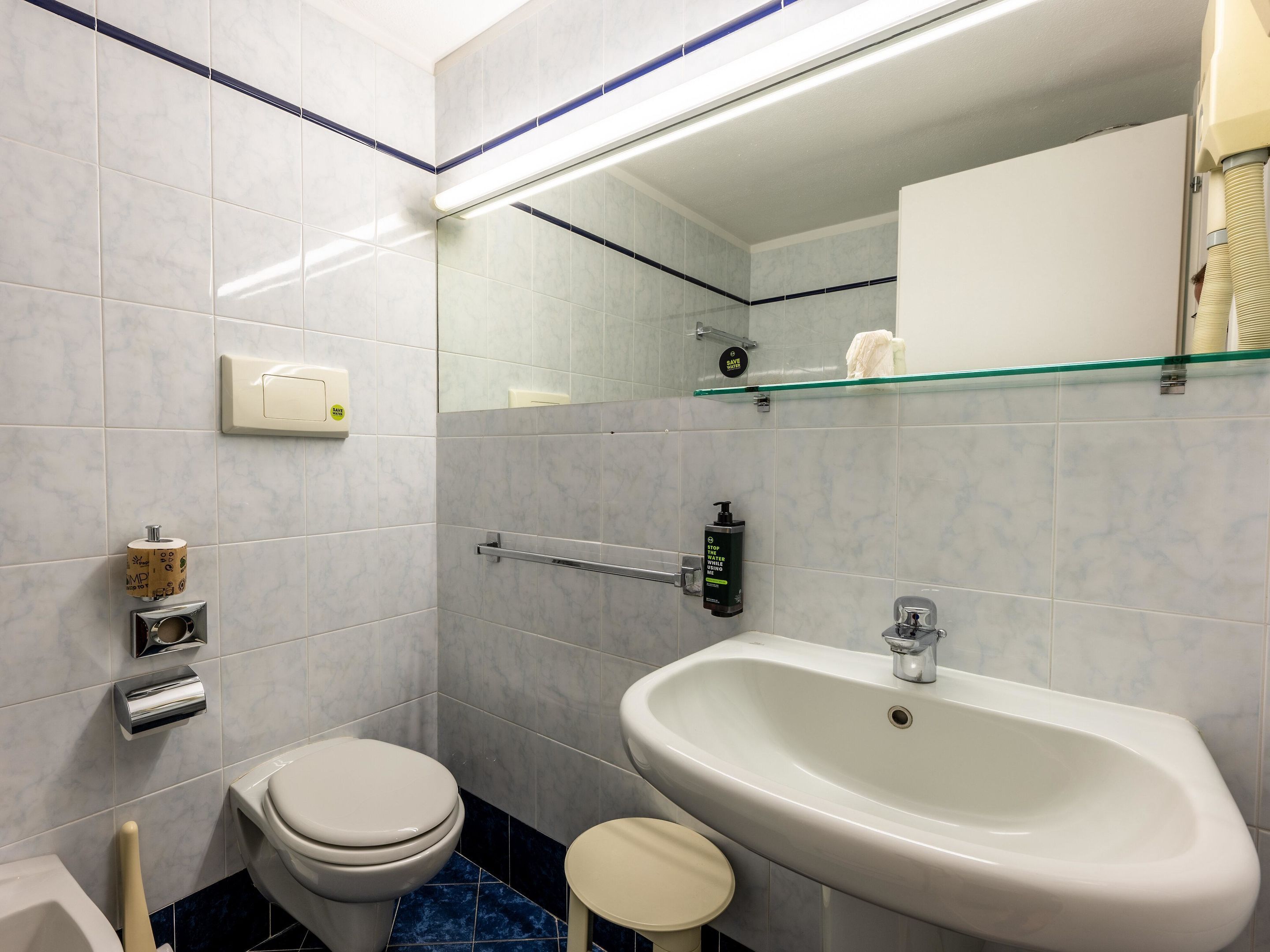 A bathroom with a toilet, sink, and mirror.