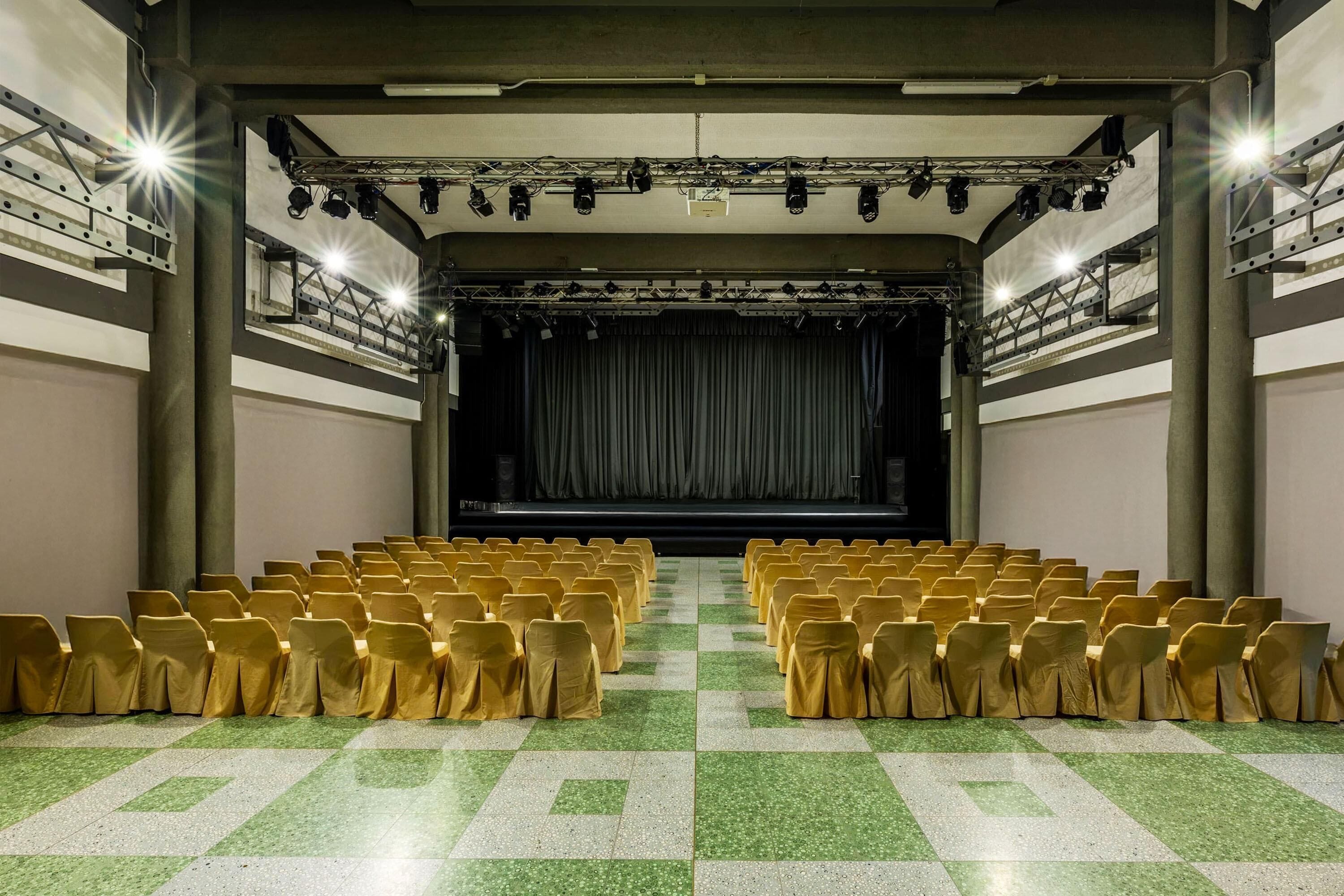 Un teatro con hileras de sillas y un escenario.
