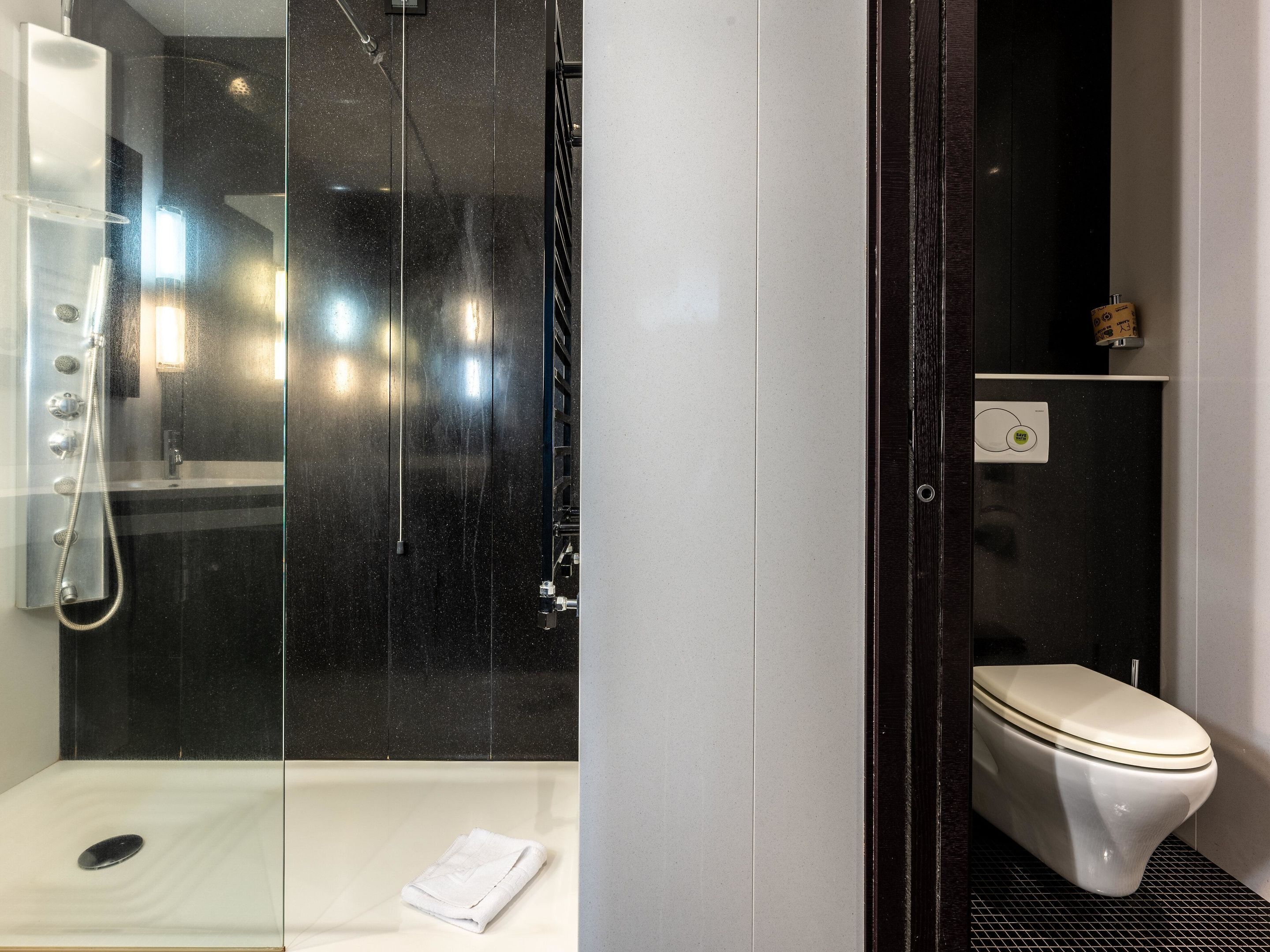 A modern bathroom with a glass-enclosed shower, a toilet, and a sink.