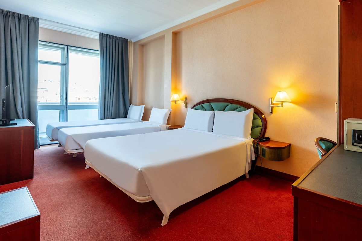 A hotel room with two beds, a desk, and a television.