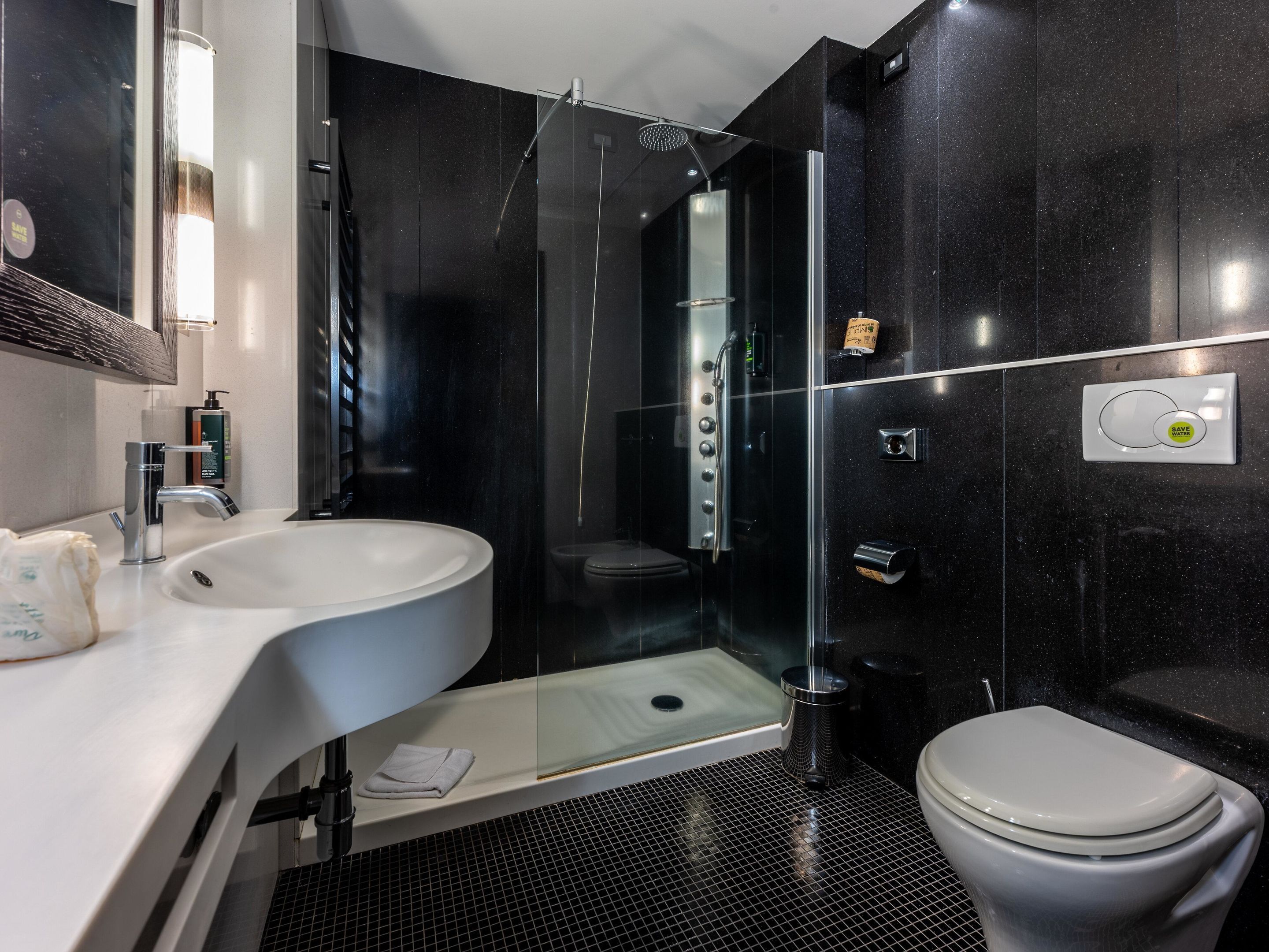 Un baño moderno con un lavamanos blanco, cabina de ducha con mampara de vidrio y un inodoro.