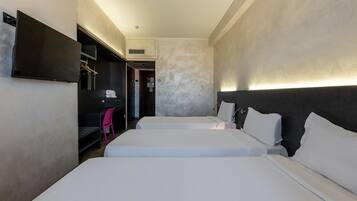 A hotel room with two beds, a TV mounted on the wall, a desk with a chair, and a wardrobe.