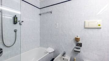 Une salle de bain équipée d’une baignoire, d’une douche, d’un bidet, de toilettes et d’un porte-serviettes.
