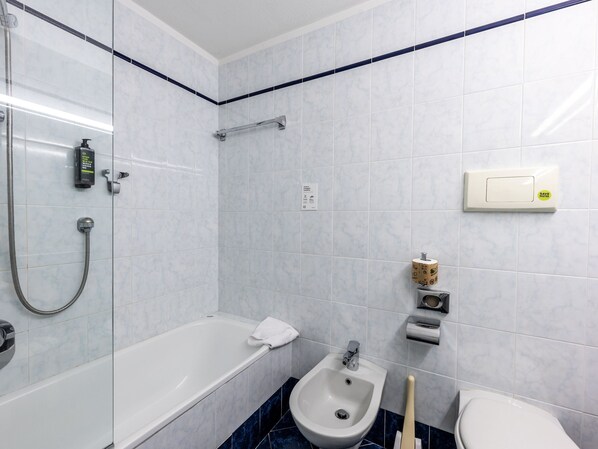 A bathroom with a bathtub, shower, bidet, toilet, and towel rack. - B&B Hotel Borgaro Torinese (Borgaro Torinese)
