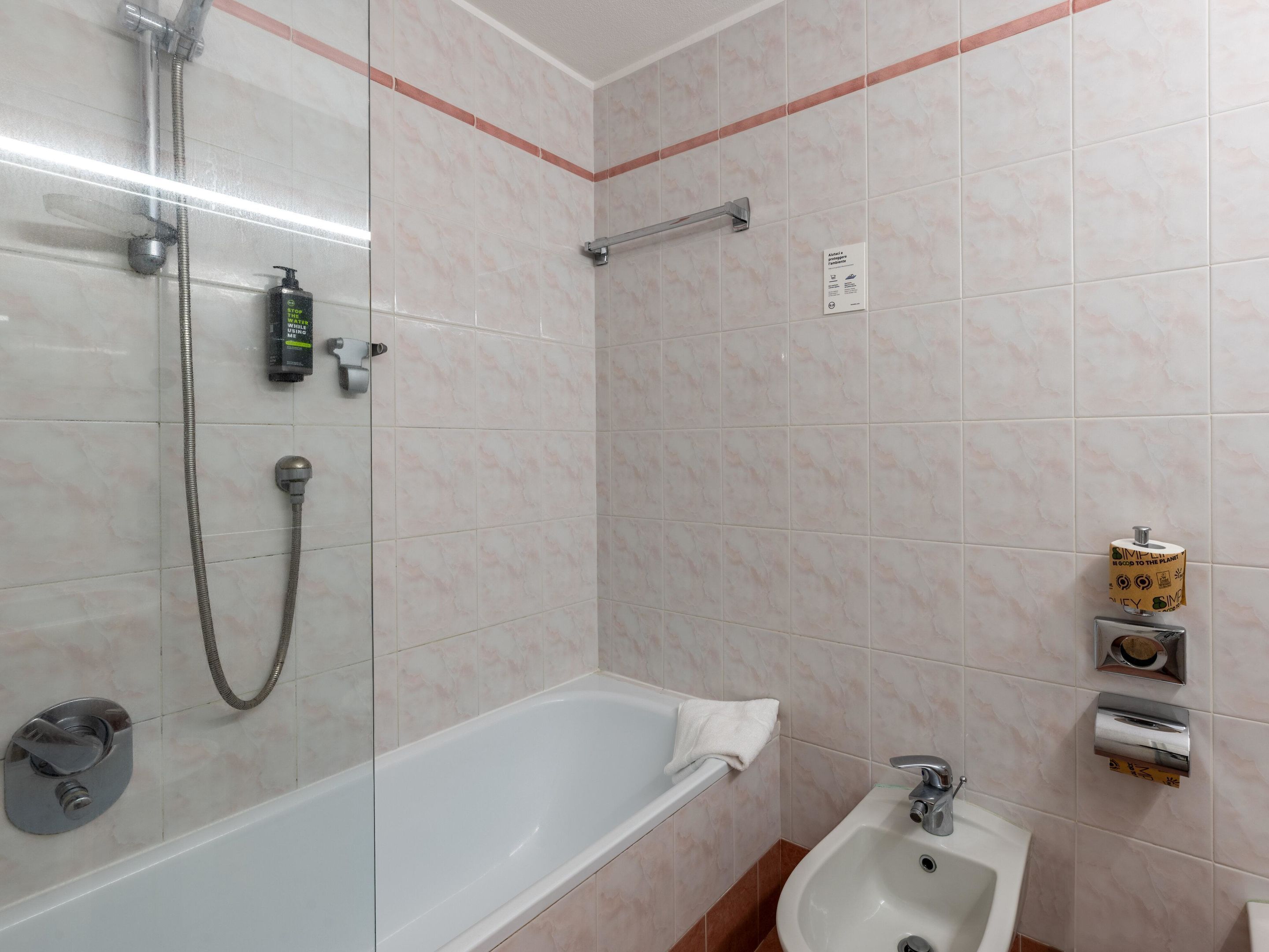 Un baño con ducha de mampara de vidrio, una bañera blanca y un lavabo.