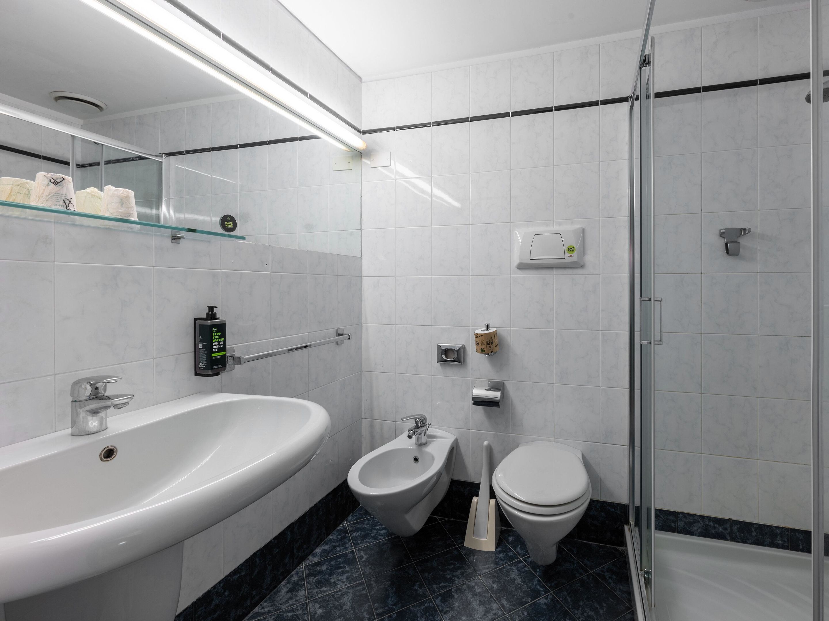 Une salle de bain moderne équipée d’une baignoire, d’un bidet, de toilettes et d’une douche à parois de verre.