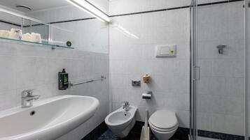 Une salle de bain moderne équipée d’une baignoire, d’un bidet, de toilettes et d’une douche à parois de verre.