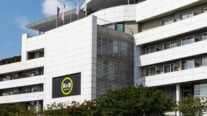 A modern B&B hotel with a prominent sign, multiple floors, and a flat roof with flags. - B&B Hotel Borgaro Torinese (Borgaro Torinese)