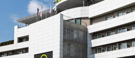 A modern B&B hotel with a prominent sign, multiple floors, and a flat roof with flags.