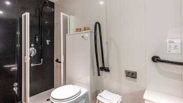 A modern bathroom with a glass-enclosed shower, a white toilet, and a small white stool.