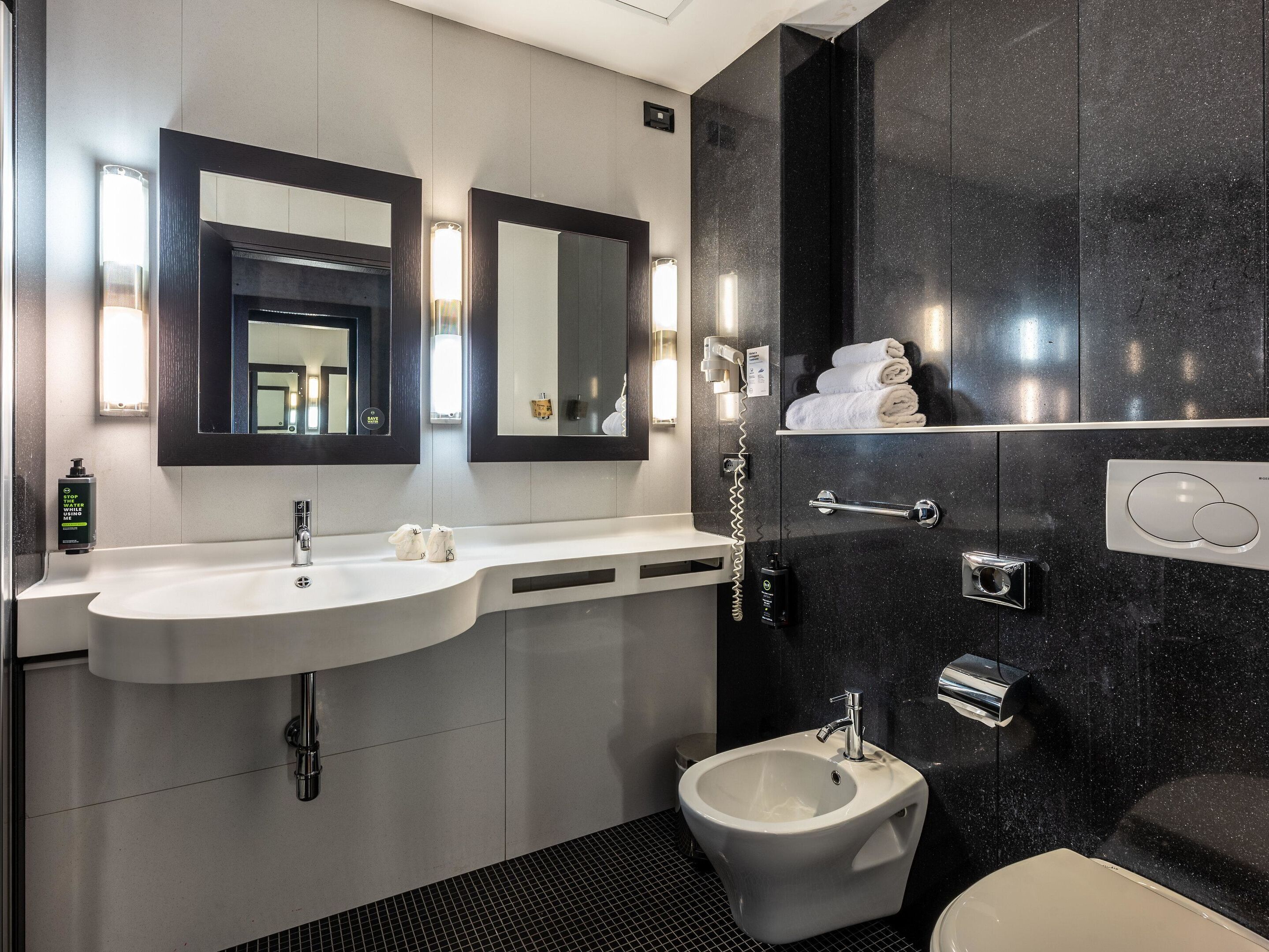 Un baño moderno con un tocador de doble lavabo, un bidé y un espejo grande.