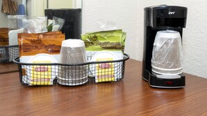A coffee machine and a basket with Lipton tea bags and a tea infuser on a wooden table. - Red Roof Inn Meridian (Meridian)